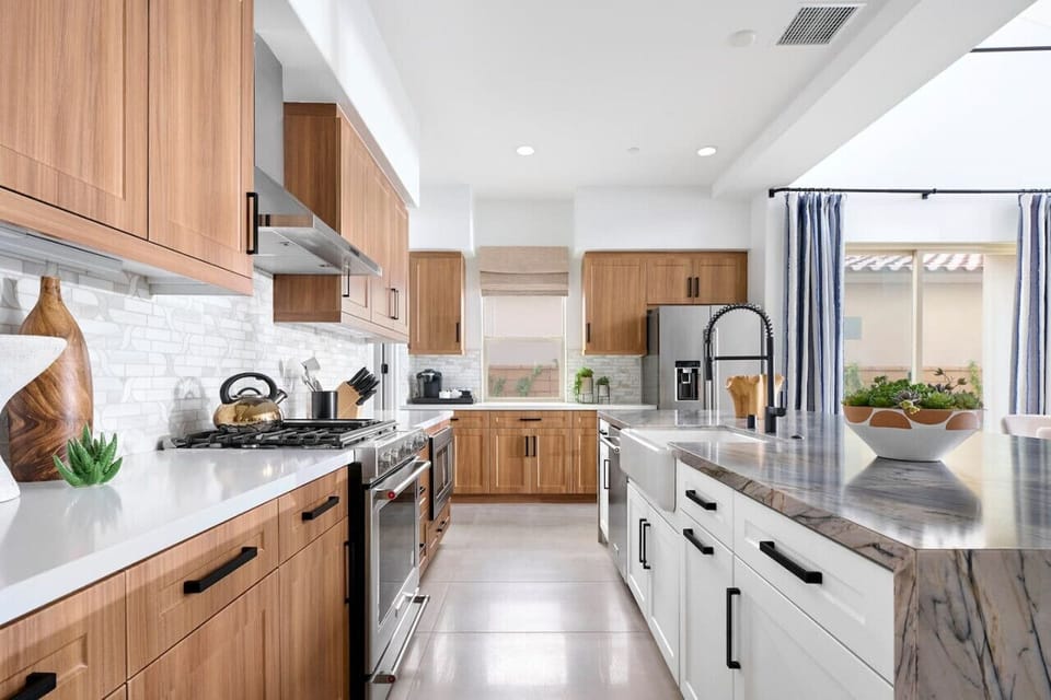 Fully equipped kitchen w/ sleek countertops, wood cabinetry & stainless steel appliances