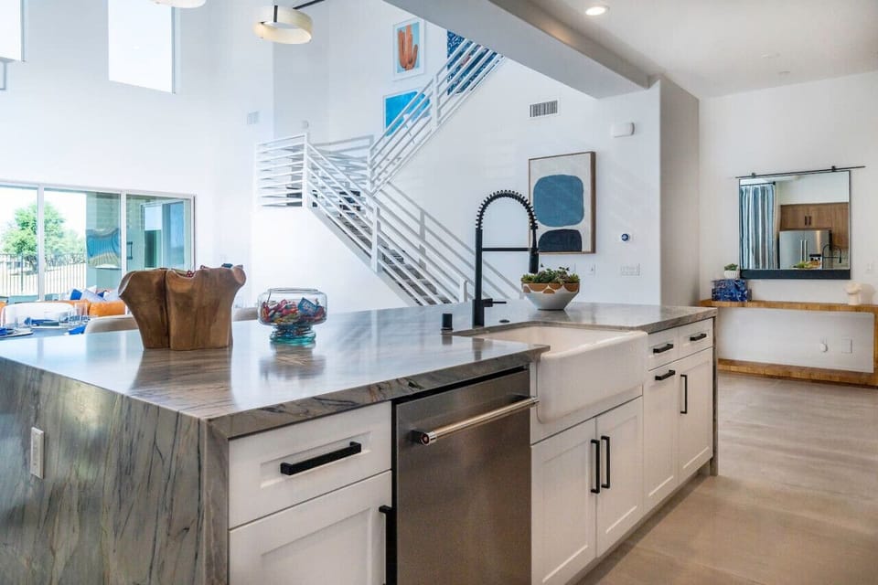 Bright kitchen island w/ waterfall edge & open railing overlooking the living area