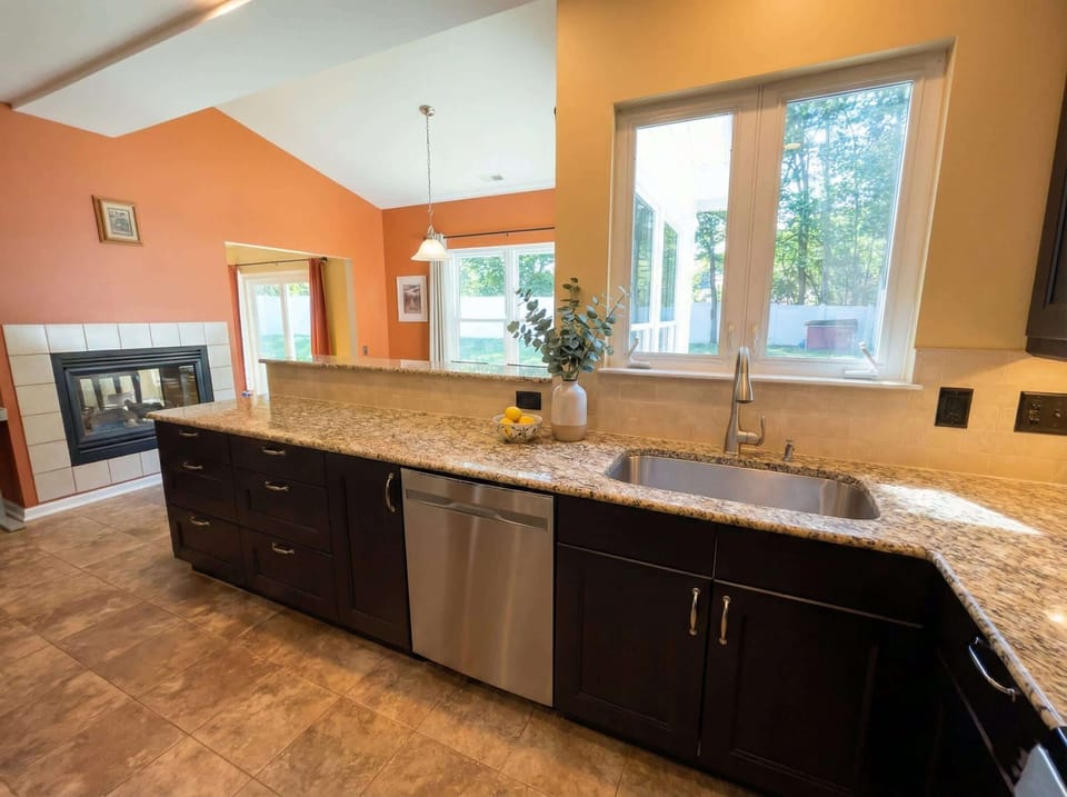 Kitchen island with sink, dishwasher, granite counter, and view toward the living room.