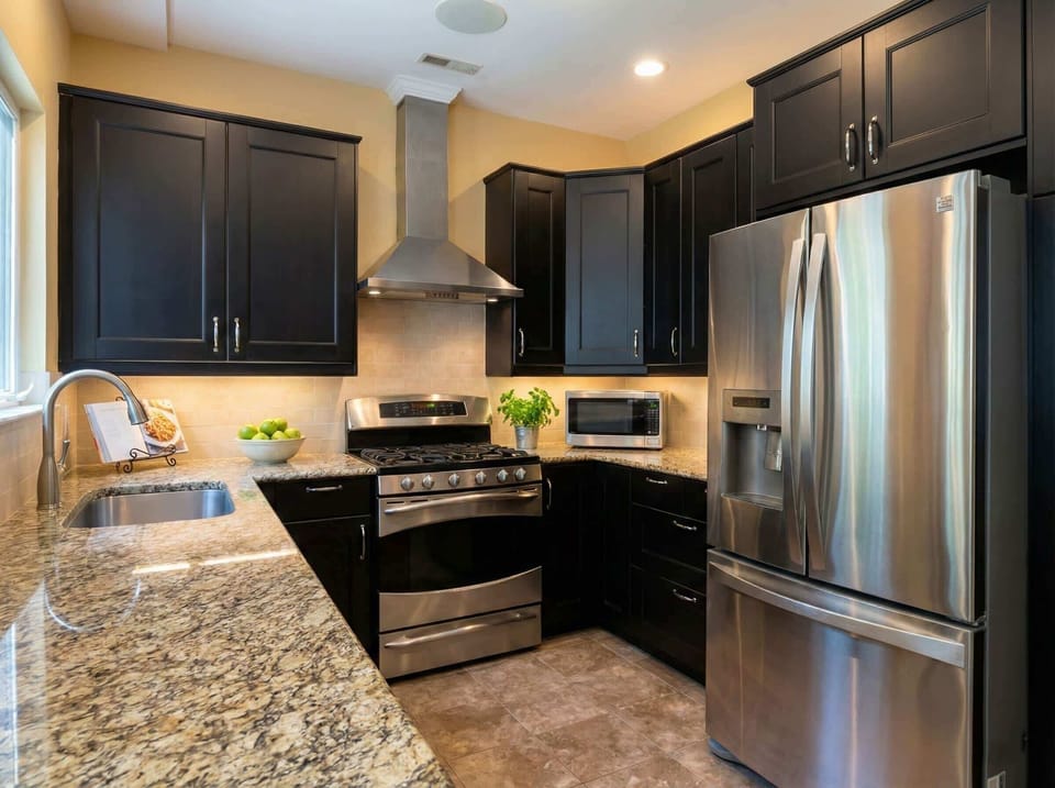 Kitchen with dark cabinetry, stainless steel appliances, granite counters, and range hood.