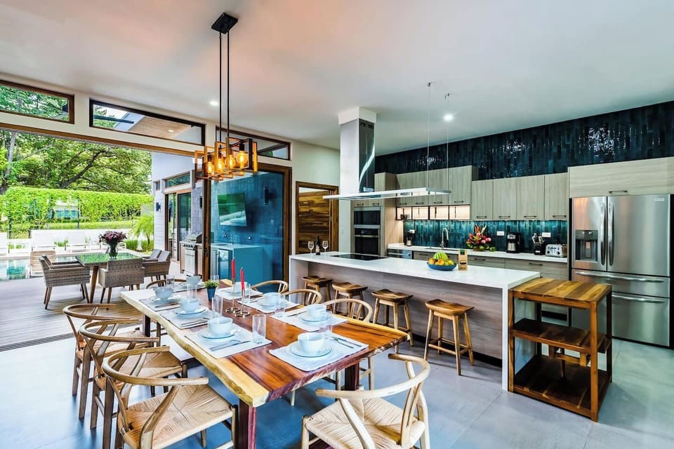 Inside this Tamarindo Villas Rental, the modern kitchen opens to a spacious dining area with a large table and counter seating—perfect for family meals and gatherings.