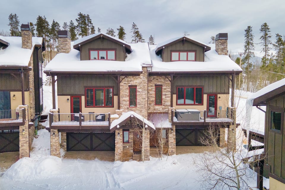 Mountain lodge with stone and timber construction nestled among snow-covered pines, offering authentic alpine architecture in a pristine winter setting.