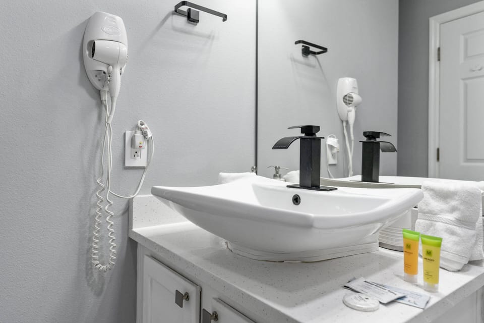 Enjoy a sophisticated stay in this well-appointed bathroom, featuring a sleek modern sink and soothing gray walls. With ample counter space and stylish fixtures, it combines functionality and comfort for your convenience.