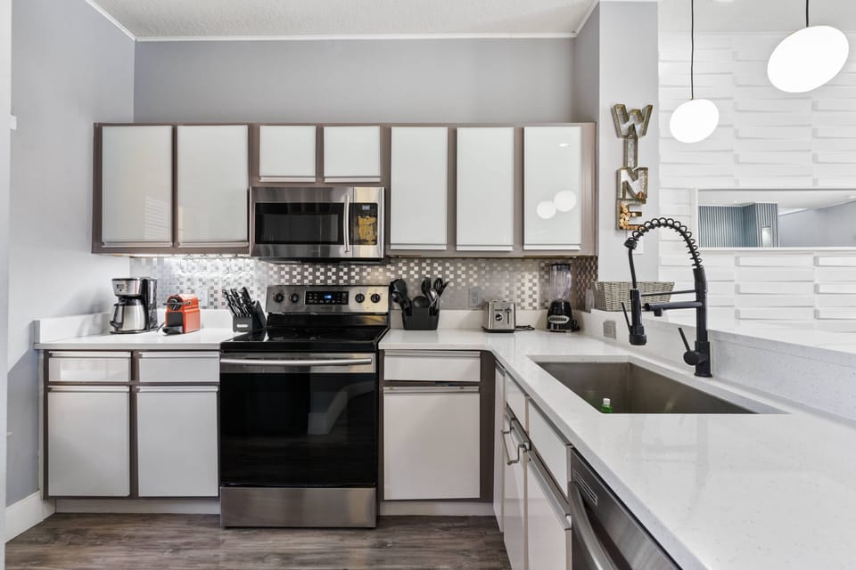 Welcome to this modern kitchen, where sleek design and functionality unite. The bold dark appliances and crisp white cabinets inspire your culinary creativity, while the stylish geometric backsplash adds a touch of sophistication.