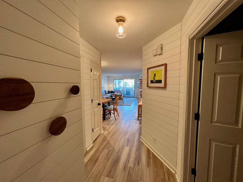 Large hallway with round wooden hooks and shiplap.