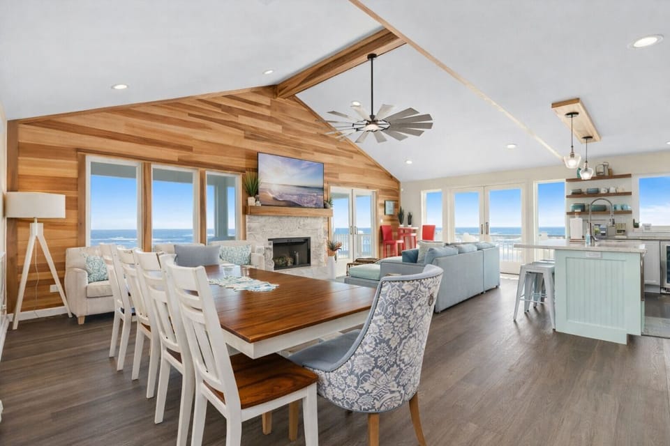 Open-concept living room with vaulted ceilings, ocean views, fireplace, and coastal décor