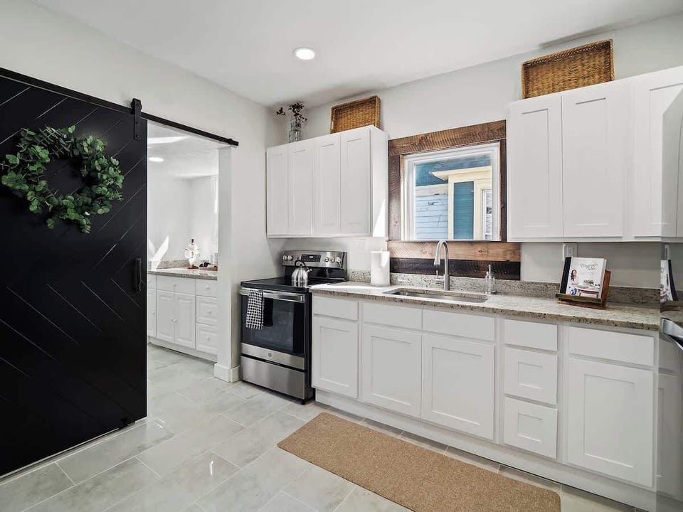 Bright kitchen w/ white cabinets, stainless stove & long granite counters