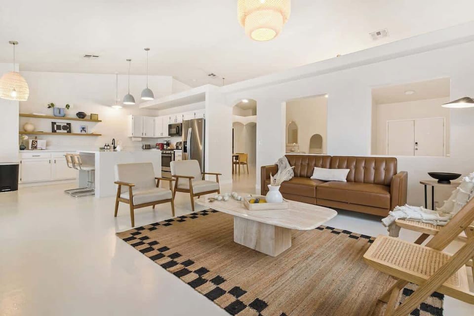 Modern boho living room with white concrete floors with kitchen access great for hosting and gathering