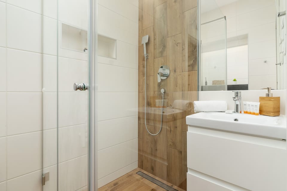A modern bathroom featuring a walk-in shower, sleek tiles, and wooden accents for a warm and clean design.
