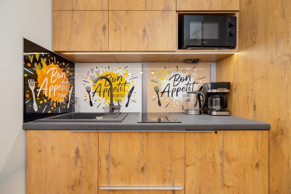 A compact kitchen area with a wooden backsplash, open shelving, and modern appliances, blending functionality and style.
