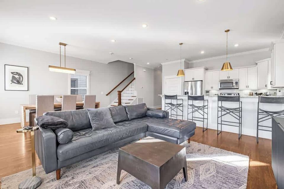Bright open-plan living with sleek kitchen, bar seating, and dining table.
