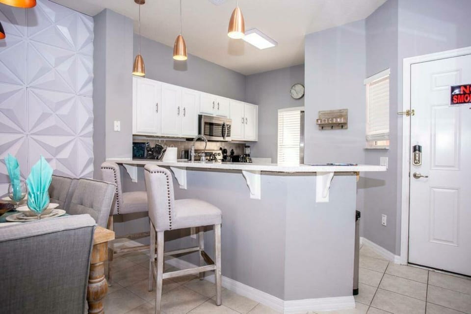 Experience a stylish kitchen with sleek white cabinets and modern stainless steel appliances, ideal for cooking together. Soft gray walls and elegant pendant lighting create a warm, inviting atmosphere for your relaxation and.