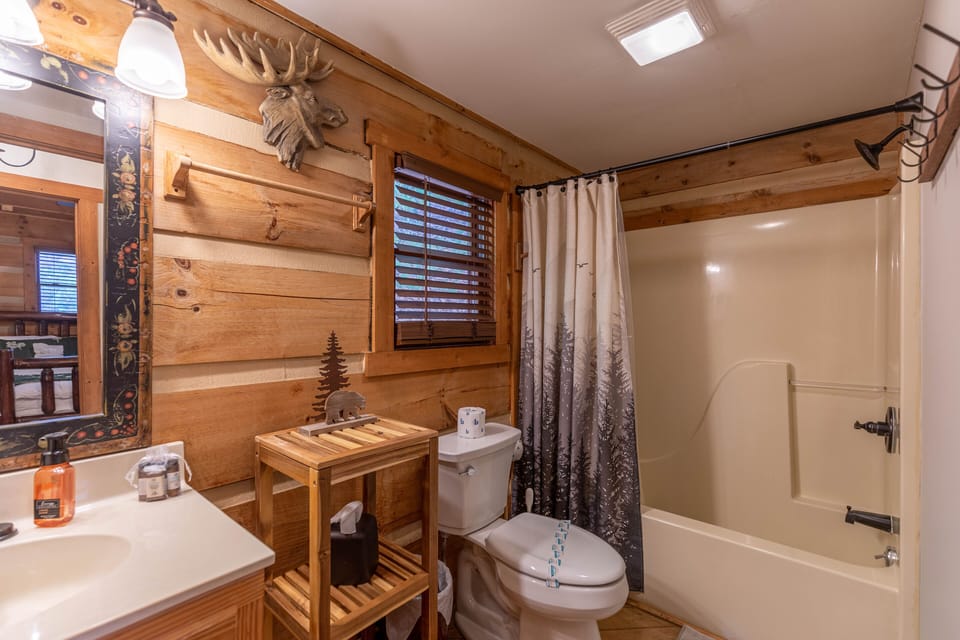 Rustic charm meets mountain personality in this full bath at Moonlight Lodge, complete with cozy log walls and whimsical woodland decor.