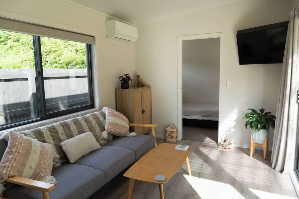 living area with smart tv, air conditioning/heat pump and looking into the single bedroom. the queen bedroom is on the other side of the living area ie behind the photographer and kitchenette