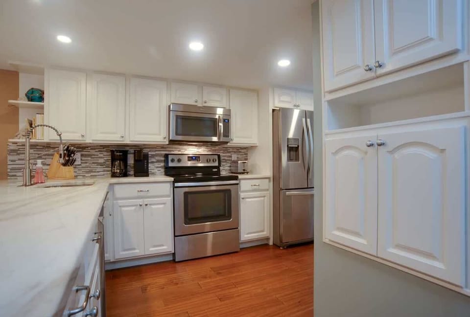 Your fully equipped kitchen features modern stainless steel appliances and elegant white cabinetry, perfect for preparing meals during your stay.