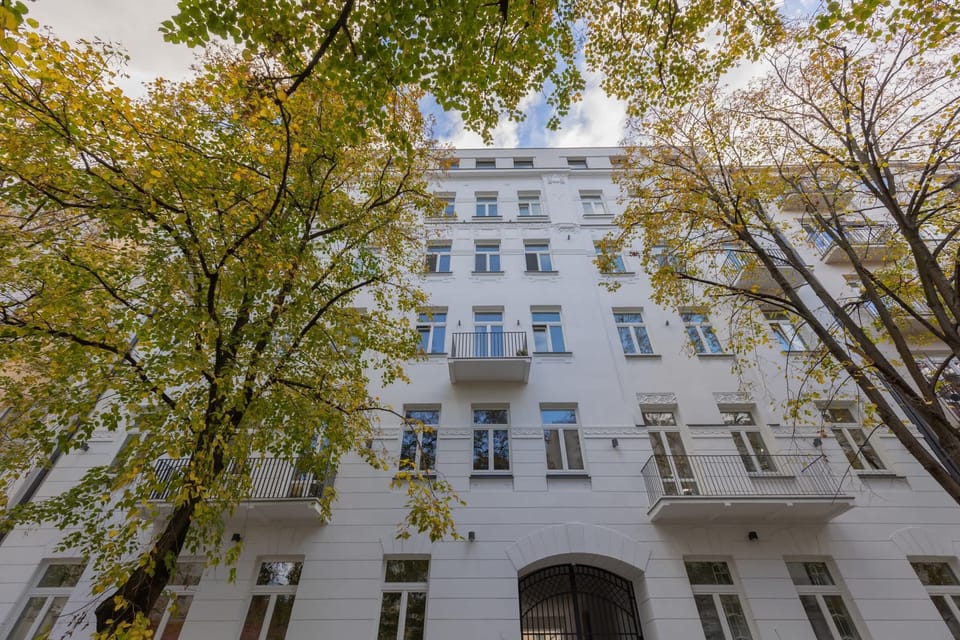 An exterior view of the building, showcasing its charming facade with tall trees adding greenery.
