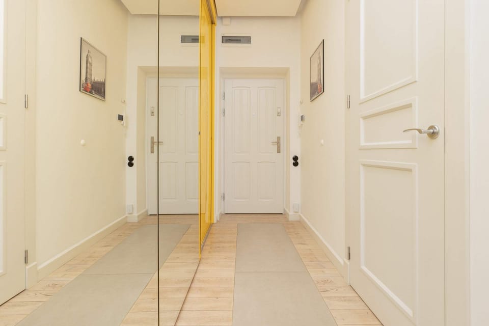 A bright hallway with clean white walls and doors, leading to the apartment.

