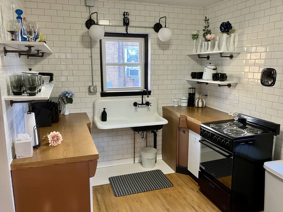 Our kitchen with coffee maker, microwave, stove, fridge, plates, cups, utensils.