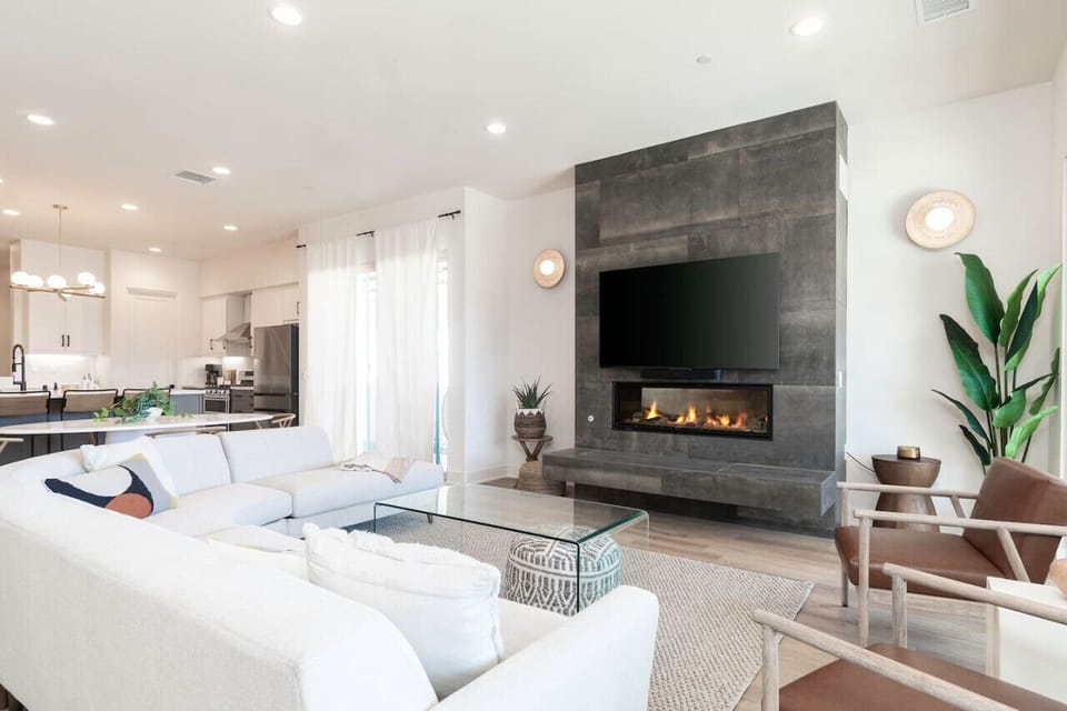 Modern living space w/ fireplace, wall-mounted TV & open flow into the kitchen