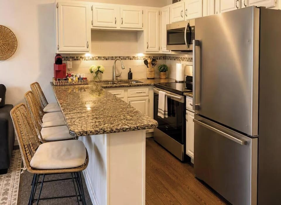 Granite breakfast bar with stools and stainless steel appliances.