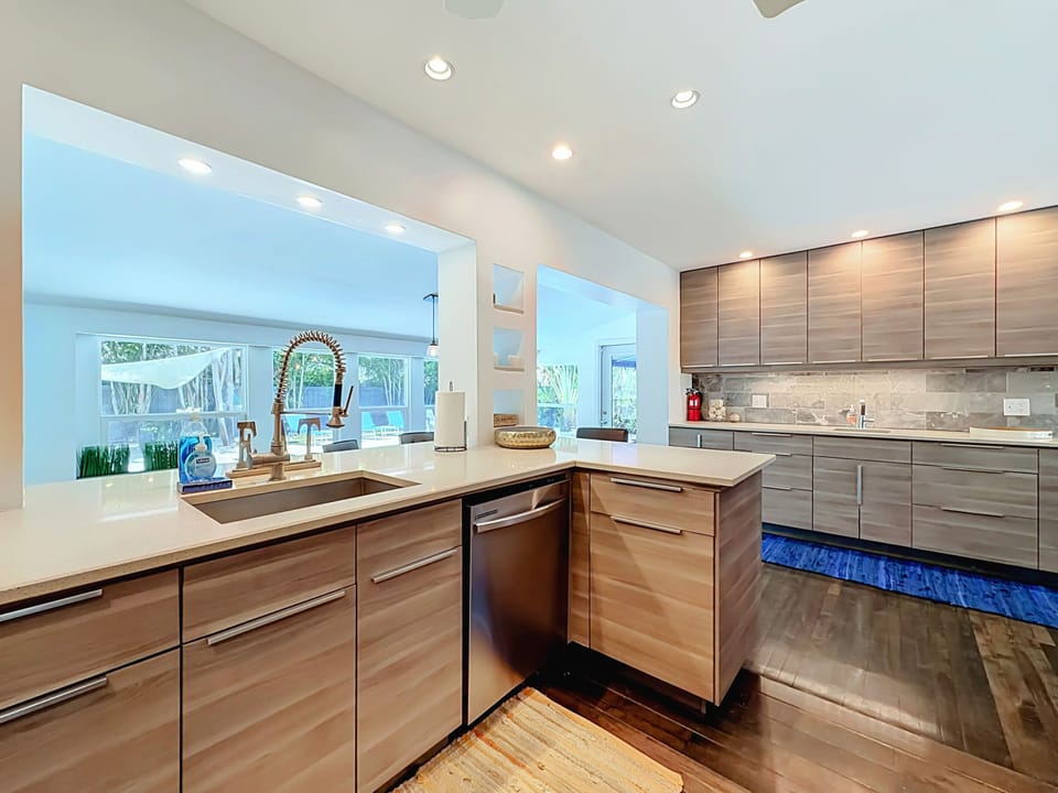 Fully equipped open kitchen with quartz countertops and pass-through window to the pool.