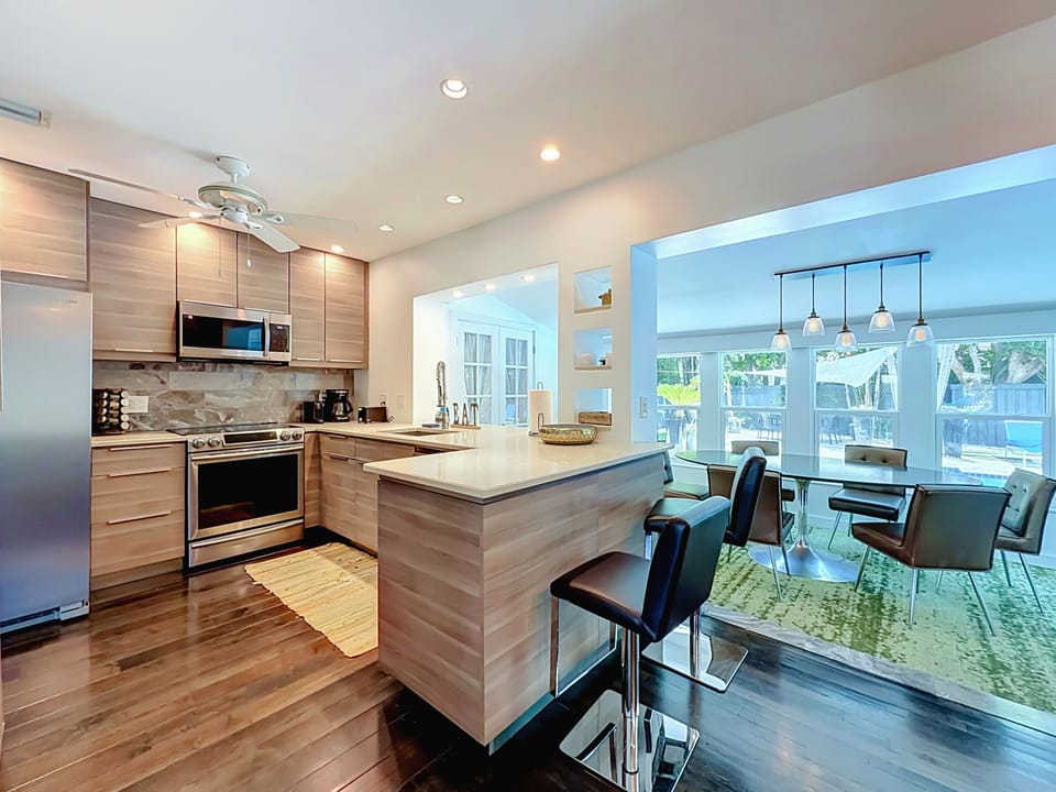 Modern kitchen with stainless steel appliances, breakfast bar seating and wood cabinetry.