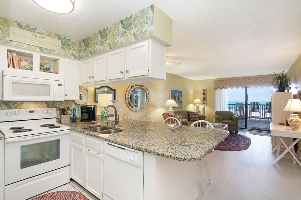 Your beachfront kitchen features granite counters and modern appliances, opening to a living space with stunning ocean views.