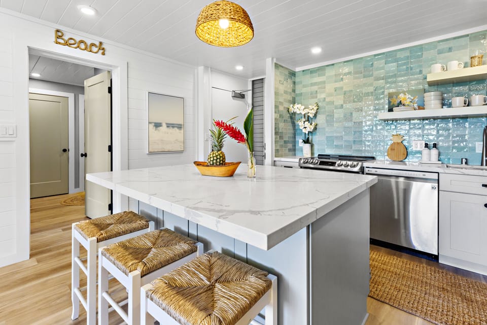Kitchen Island with Quartz Countertops - Beautiful oversized island with quartz surfaces, bar seating, and a view into the fully updated coastal-style kitchen.