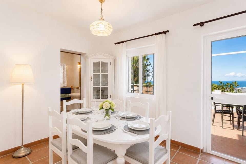 Open-plan living room with sofas, dining area, kitchen, ornamental fireplace, A/C, WiFi internet, satellite TV, and sea views