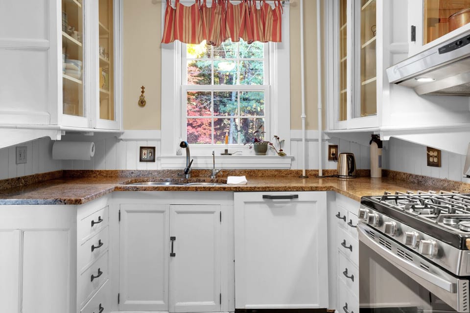 Kitchen workspace with granite counters, gas range, and a window overlooking the fall colors