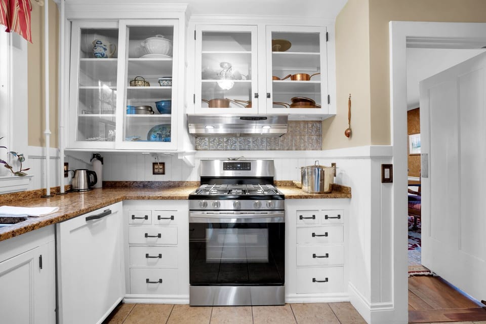 Fully equipped kitchen with gas range, granite countertops, and glass-front cabinetry