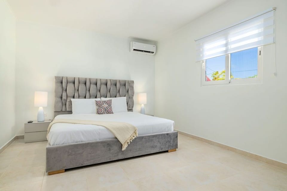 An air-conditioned bedroom with a comfortable bed. There is flat screen TV, ensuite bathroom, and closet