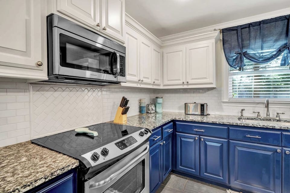 Whip up your favorite meals in this fully equipped kitchen, featuring bold blue cabinetry, modern appliances, and plenty of counter space. Bright, stylish, and functional—perfect for everything from quick breakfasts to family feasts.