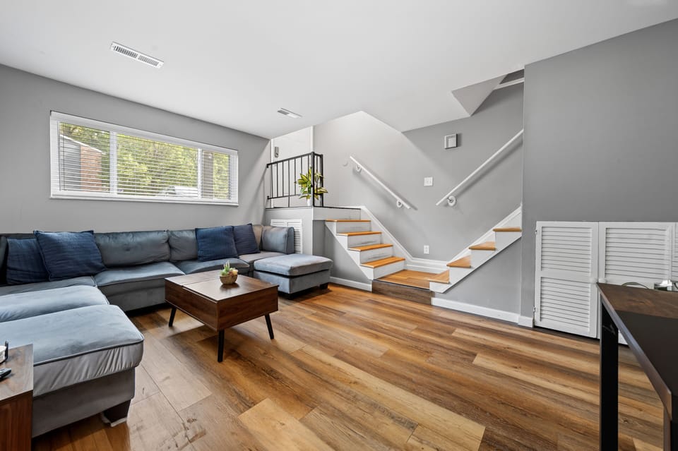Living room; Unit entry way stairs on the left, and stairs leading upstairs on the right.