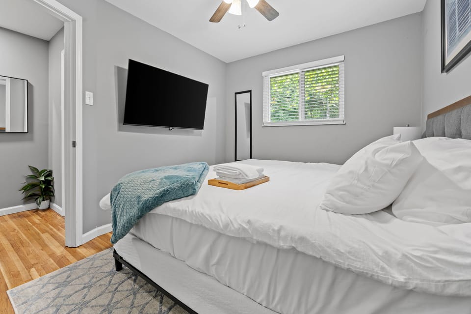The reverse view of the second bedroom shows the king bed, wall-mounted TV, window, ceiling fan, and full-length mirror.