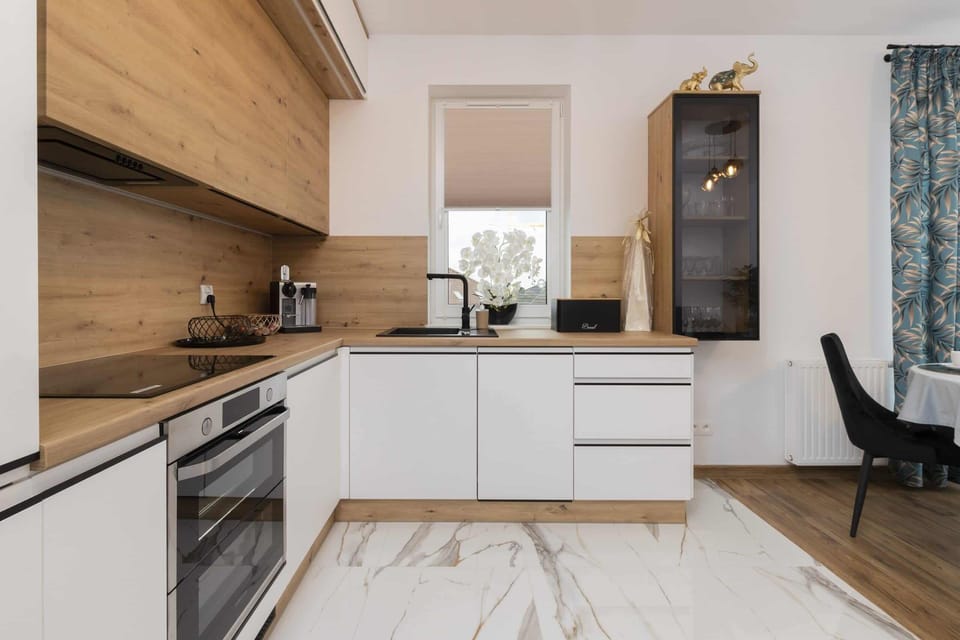 A modern kitchen with wooden cabinetry, white countertops, and a built-in oven.
