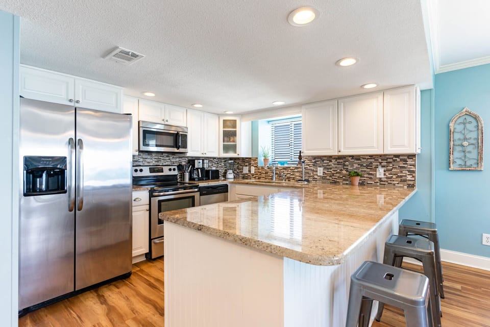Your gourmet kitchen awaits with gleaming granite counters, stainless appliances, and breakfast bar seating—perfect for morning coffee or evening meals.
