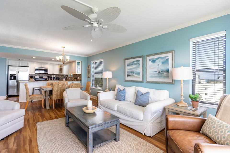 Relax in your bright, coastal-inspired living space with plush seating, ceiling fan comfort, and an open kitchen perfect for preparing meals together.