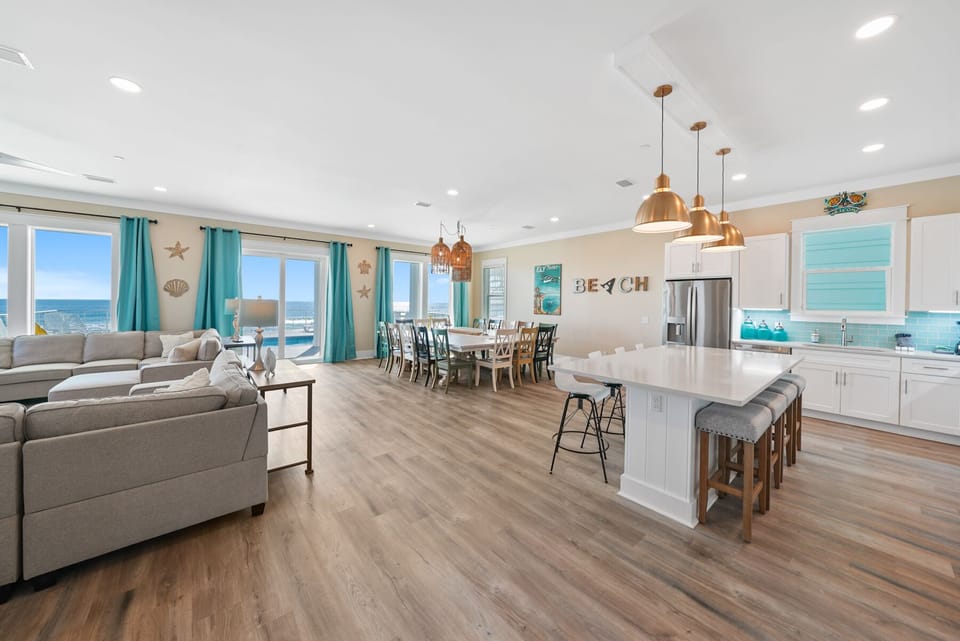 Your spacious beach house opens to stunning ocean views through wall-to-wall windows, where coastal breezes fill the bright living space.