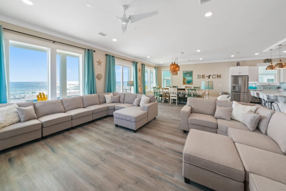 Relax in your spacious living room with plush sectional seating and stunning ocean views through floor-to-ceiling windows.