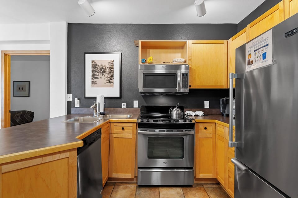 Your fully equipped kitchen awaits with stainless steel appliances, sleek countertops, and warm wood cabinets—perfect for preparing delicious meals during your stay.