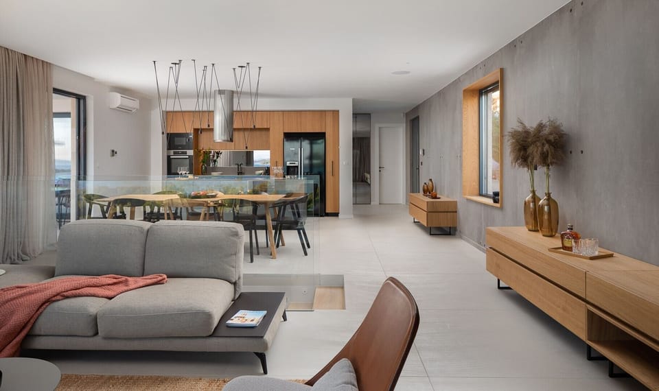 Living room with gray sofa, chairs and coffee table and kitchen with living area