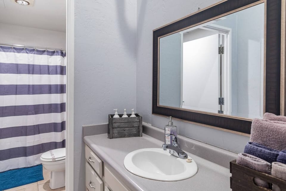 A Full Restroom with a hair dryer, shampoo, body wash, towels, toilet paper and conditioner