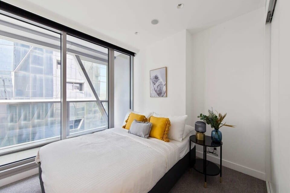 A bedroom with a double sized bed & plush pillows.