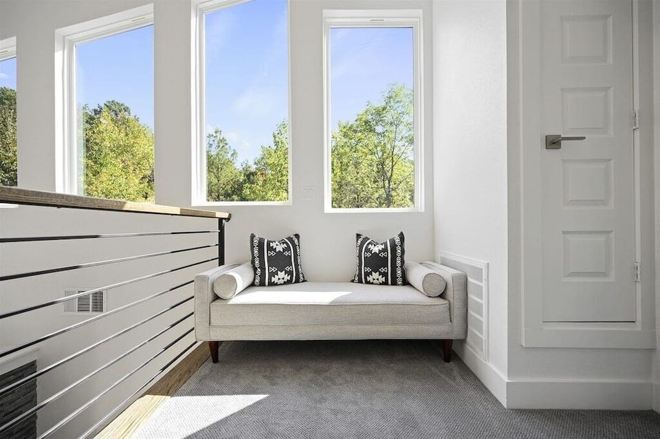 Sunlit Nook: Relax on a stylish daybed with panoramic views of lush greenery!