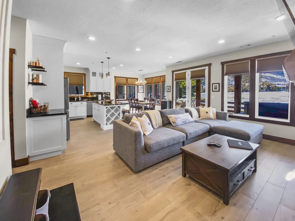 Enjoy this modern open-concept space featuring a large sectional sofa, fully equipped kitchen with an island, and access to the outdoors.