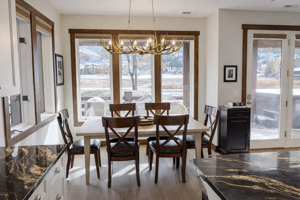 Gather for memorable meals in this bright dining space with mountain views and elegant antler chandelier creating perfect ambiance.