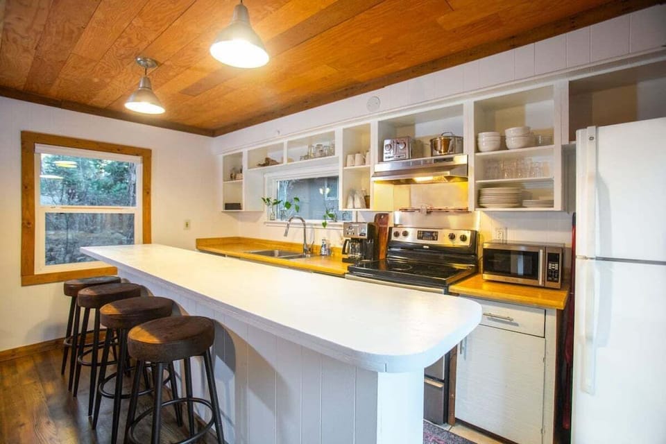 The kitchen features stainless steel appliances, charming exposed shelving, and a large kitchen bar with seating for 6.