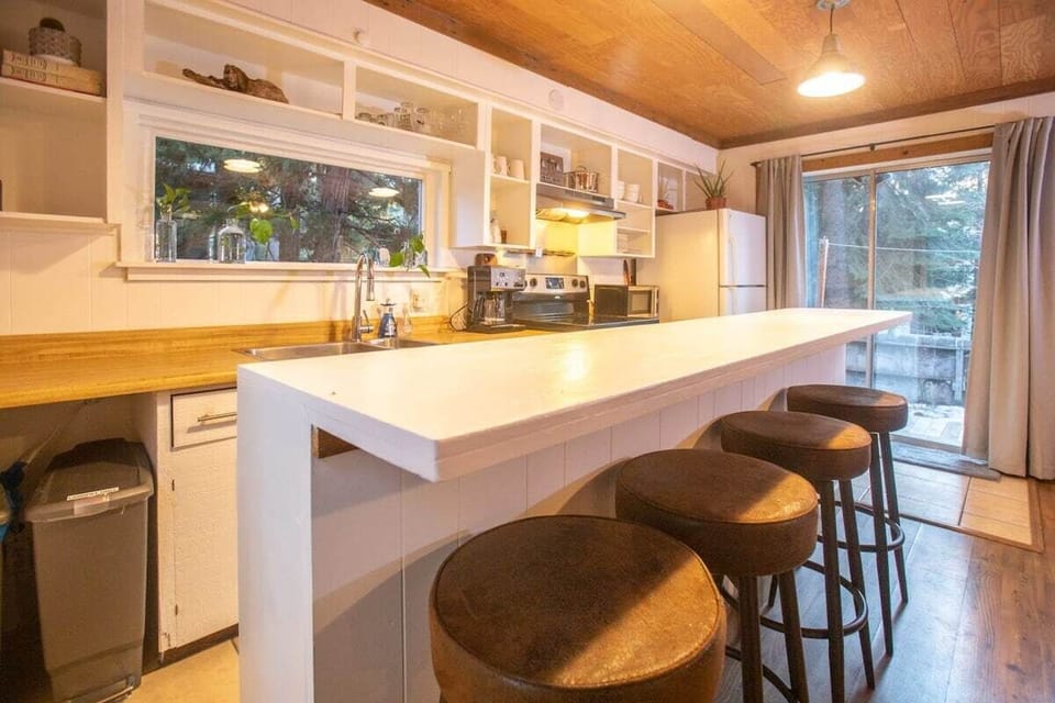 The kitchen features stainless steel appliances, charming exposed shelving, and a large kitchen bar with seating for 6.