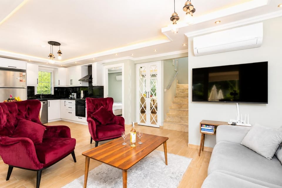 Open-plan living room with sofa, dining area, kitchen, A/C, WiFi internet, and satellite TV